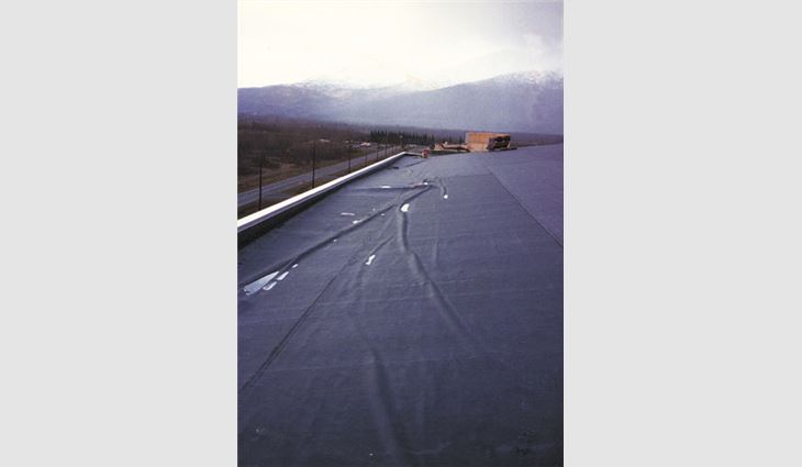 A fully adhered EPDM membrane was installed over mechanically attached polyisocyanurate insulation over a vapor retarder on a metal deck. The hangar's sides had a parapet, and the ends had metal edge flashings. Air was able to enter under the edge flashings at the profiled metal wall panels and cause the membrane and insulation facer to separate from the foam insulation. A substantial amount of membrane detached from the insulation, and one of thefield seams ruptured (a secondary failure that occurred after the membrane detached). 