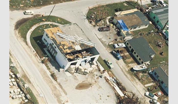 A precast concrete twin-tee deck panel was lifted and thrown back toward the center of this roof. Three large roll-up doors collapsed, which increased the internal air pressure in the building and uplift load on the deck. Although precast deck panels are heavy, they need to be anchored to resist large uplift loads.
