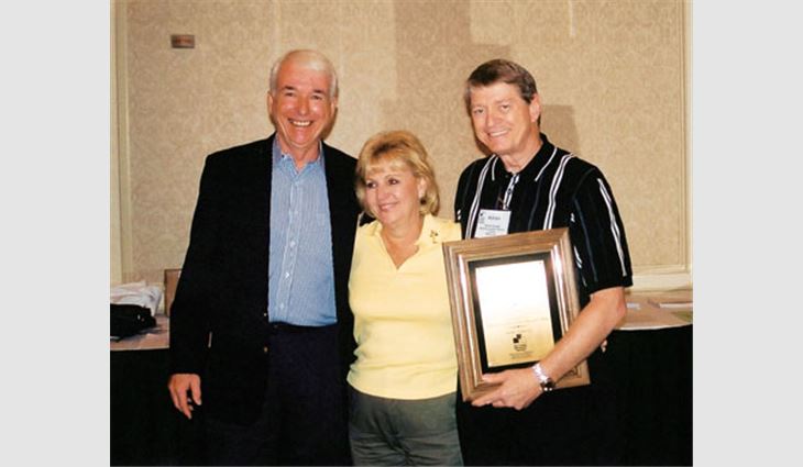 Winner of the Martin A. Davis RCMA Industry Leadership Award Adrian Berger (right), vice president of Seaboard Asphalt Products Co., Baltimore, poses with his wife, Etta, and Tim Nelligan, president of RGM Coatings, Fresno, Calif., during the Roof Coatings Manufacturers Association's Annual Conference & EXPO. Nelligan, who won the award in 1995, presented this year's award to Berger.