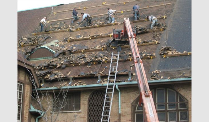 Workers replace the asphalt shingle roof system with clay tile.