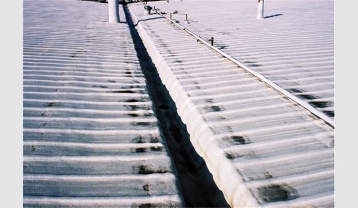 This photo shows a large existing warehouse complex that had been reroofed with SPF in 1991. The existing metal roof and interior gutter system were overlayed with 1  1/2 inches (38 mm) of SPF and coating. The existing metal flashing system was secured and covered with SPF. No new metal flashings or counterflashings were added. The interior gutters also were covered with SPF as shown.