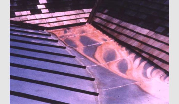 Photo 2: This photo shows corrosion on a low-slope copper roof system in Westchester County, N.Y., that receives runoff from a steep-slope cedar shingle roof system. Note there is no corrosion on the low-slope copper roof system receiving runoff from the steep-slope copper roof system.