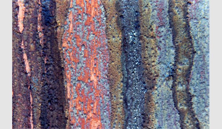 Photo 5: This is a magnified photo of an open-front rainwater leader showing copper corrosion. Note the corrosion pits. The gold-colored areas are bare copper; black areas probably are copper oxide or copper sulfide; blue and green areas probably are copper sulfate.