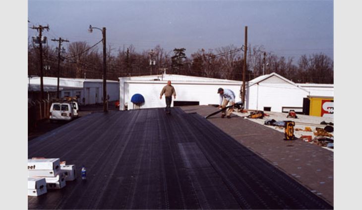 This picture shows roofing workers applying the base sheet. 