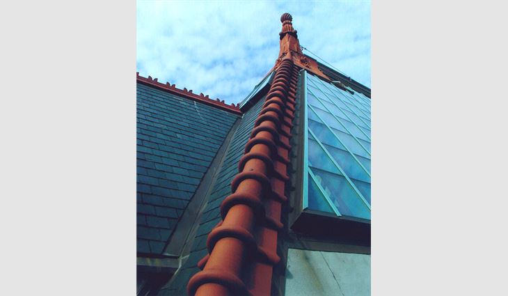 This photo shows the completed tile and slate roof systems, as well as the skylight and finial.