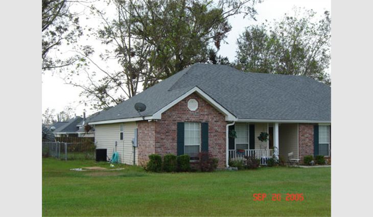 Photo 7. This house east of Picayune, Miss., is about 25 miles (40 km) north of the coast along Route 43. The newer asphalt shingle roof system fared well except for the hip shingles above the television satellite dish.