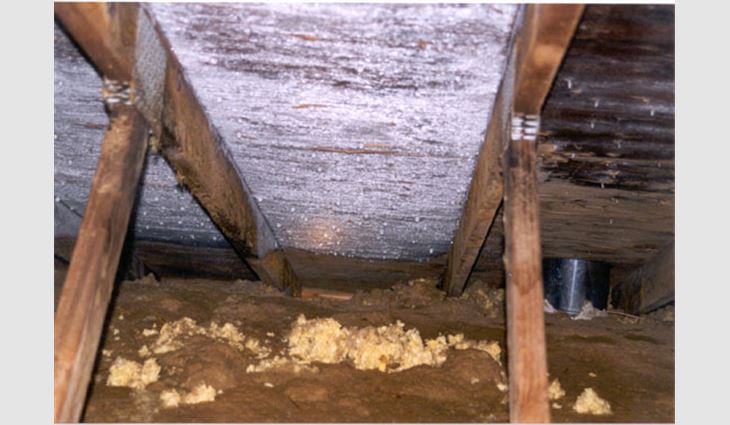 Photo 2: This photo shows frost and melting ice on the underside of the roof deck. Note the brown staining on the loose-fill insulation.