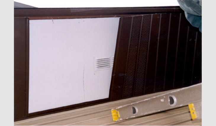 Photo 3: These were the conditions at an inspection opening in the roof eave. At this location, new aluminum panels were installed over the original plywood soffit panels. The vents in the aluminum panels were spaced at 3 feet (1 m) and did not coincide with the vents in the underlying plywood soffit (spaced at 8 feet [2.4 m]).
