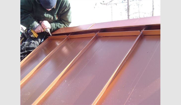 As the wind is diverted around the baffles and over the ridge cap, negative air pressure is created, increasing the air flow out of the roof system. The baffles are applied to the roof panels on a 1-inch (25-mm) butyl tape and screwed down with gasketed fasteners. It is important to leave a gap at the sides of the baffles for water to drain from the ridge assembly. 