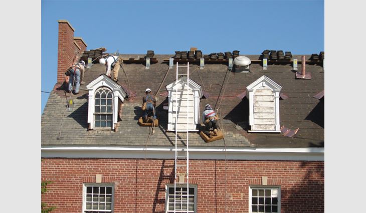 Workers install salvaged slate on Building 13.
