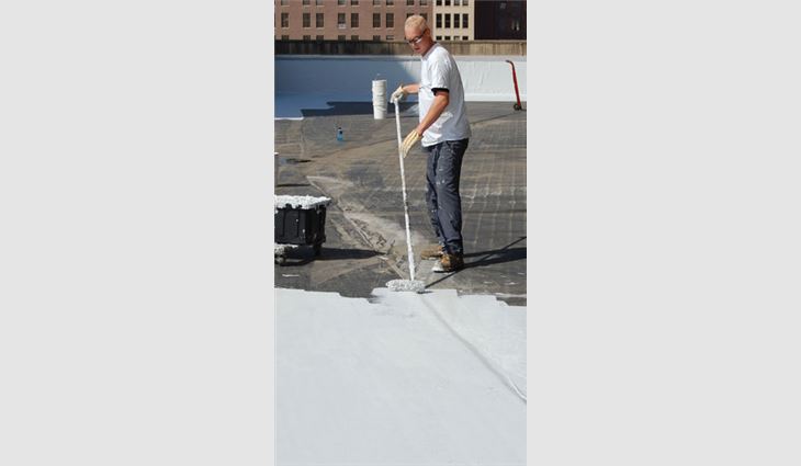 A worker rolls a coating on an EPDM roof system.