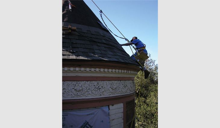 A worker installs shingles on the oblong-shaped steeple