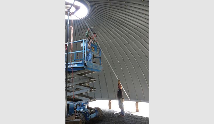 A worker installs material over a 4-foot opening at a dome's top ring.