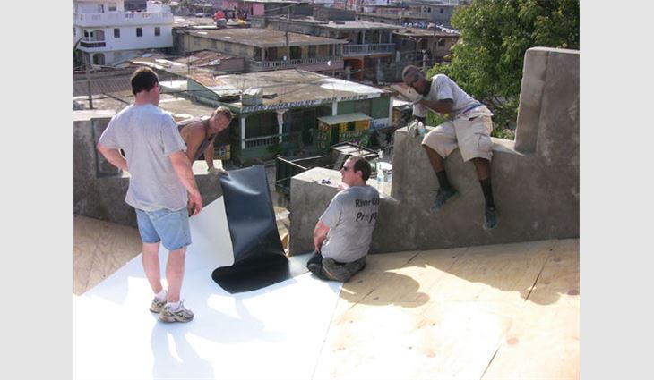 Workers install the roof membrane in a valley