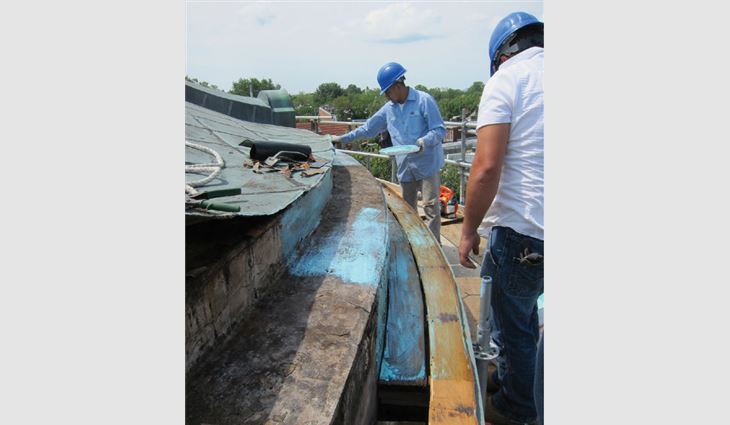 Workers restore the existing flat-seam roof and built-in gutter. 