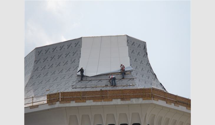 Workers apply the TPO membrane
