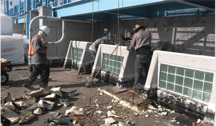 Workers demolish the existing built-up roof system