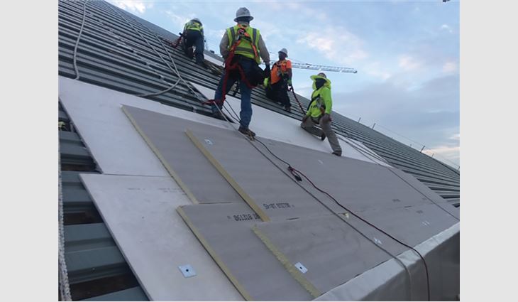 Workers install new standing-seam Galvalume® panels.