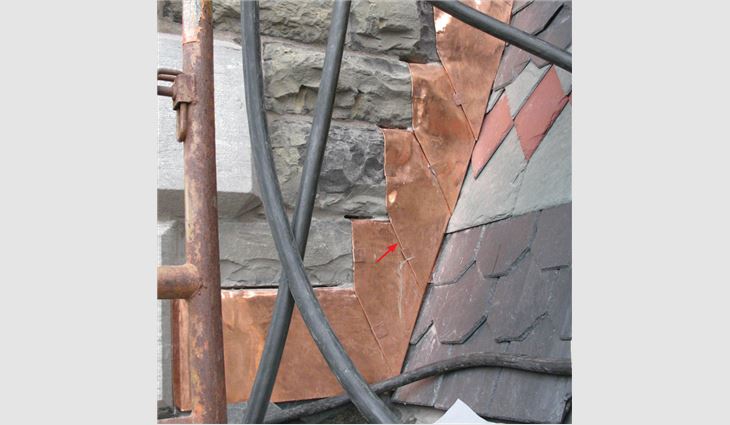 Photo 1: The lower corners of these soft copper counterflashings have been
angled back toward the roof to help minimize their apparent size (red arrow),
and their bottom ends are hemmed and loose-locked together to help
prevent outward displacement.