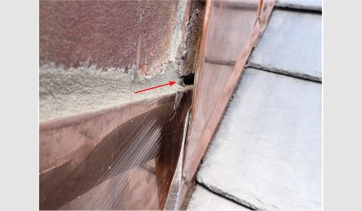 Photo 3: Lack of coordination between the roofing contractor and masonry
contractor led to the concealed portion of the underlying counterflashing’s
reglet not being filled with mortar before installation of the overlying
counterflashing (red arrow).