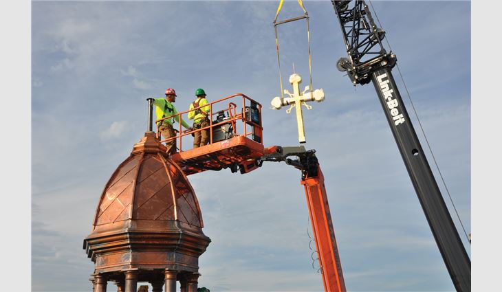 Workers reinstall a new gold-leafed
copper cross on a restored dome
