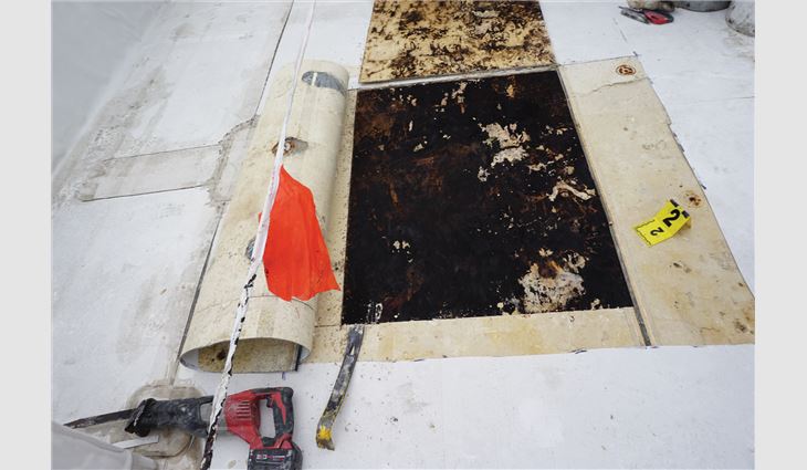 Photo 3: Another investigative opening made into a soft roof in a northern climate shows a gypsum cover board present. Both the gypsum cover board and oriented strand board roof deck are saturated and cannot support any load. Effectively, only the single-ply roof membrane is preventing people from falling through. 