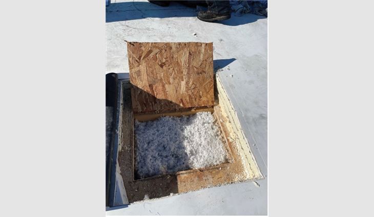 A view of a cold roof in a northern climate with blown insulation. There are numerous soft spots and decayed decking throughout this roof. However, in areas like this where a polyisocyanurate saddle is installed between drains, the oriented strand board is in pristine condition. 