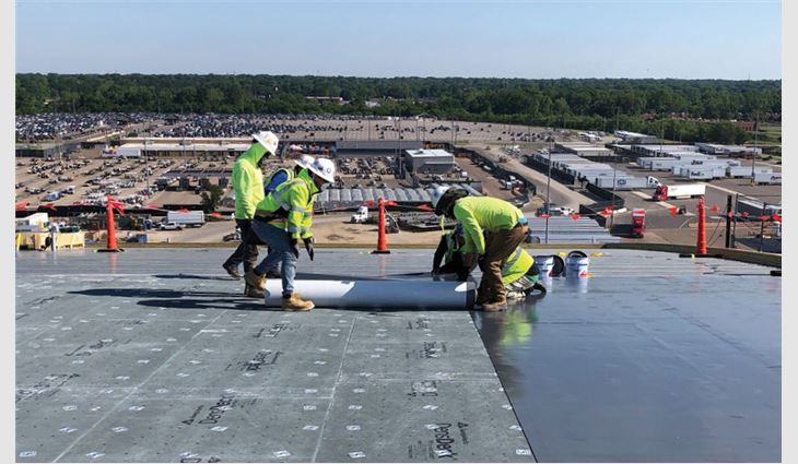 Crew members unroll the top layer of membrane